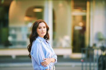 Wall Mural - Fashion portrait of beautiful young woman, wearing blue shirt, posing outdoors