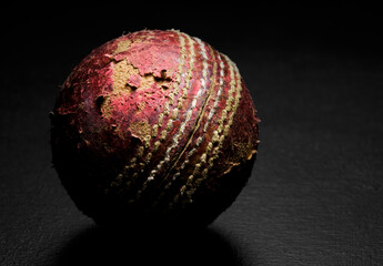 Wall Mural - Close-up of a leather cricket ball on a black background fine art