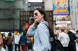 © PR Image Factory - cool stylish Asian woman wearing sunglasses brushing hair with hand and looking into distance while posing in shinsaibashi suji and doutonbori shopping district Osaka japan