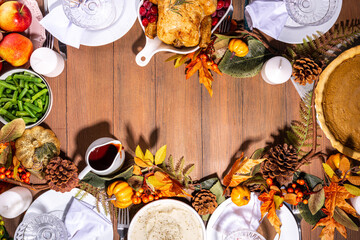 Wall Mural - Thanksgiving family party dinner table setting with plates, cutlery, glasses, traditional dishes - baked turkey or chicken, pumpkin pie, fruits, mashed potatoes, green beans, wooden background