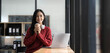 © wichayada - Smiling young Asian businesswoman holding a coffee mug and laptop at the office.