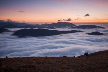Wall Mural - sunset hidden behind clouds and fog over hills, bright yellow sun on colorful cloudscape, blue viole