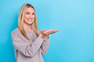 Photo of pretty lovely lady toothy smile dressed pastel pullover clothes two arm demonstrate empty space isolated on blue color background