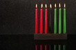 Kwanzaa festival concept with seven candles red, black and green in candlestick with reflection on black background, copy space