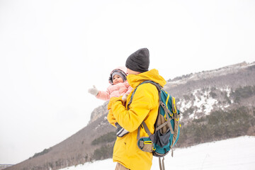 Happy father play and have fun woth baby. Man holding the female toddler in the hands and laughing on a cold winter day