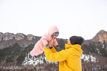 Happy father play and have fun woth baby. Man holding the female toddler in the hands and laughing on a cold winter day