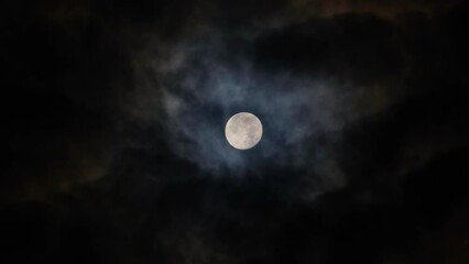 Wall Mural - Full Moon on a black cloudy night. Colored clouds passing by the Moon in spooky feeling like thriller and horror films. Dark night sky. Real video recording