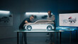 © Framestock - Experienced automotive engineers discuss the design infront of a rake sculpture prototype car model. Engineers use a touch screen digital tablet in a high tech laboratory. Make design corrections.