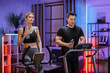 © sofiko14 - Portrait of young asian male and caucasian female wearing sportswear using exercise bike and treadmill drinking water. Home fitness workout sporty people training on exercise machines at evening time