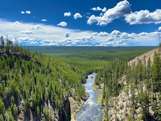 River between forested hills under a cloudy sky