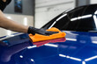 Hand car drying with microfiber in detailing auto service. Cleaner worker dry body car after washing automobile.
