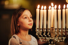 Side View Portrait Of Young Girl Looking At Menorah Candle During Hanukkah Celebrations