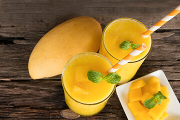 Mango smoothies orange colorful fruit juice beverage healthy high protein the taste yummy in glass on wood background from top view.
