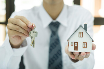 Wall Mural - Real estate agent holding house model and keys to consult client.