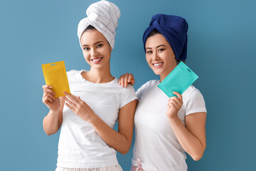 Wall Mural - Beautiful young women with facial masks on blue background