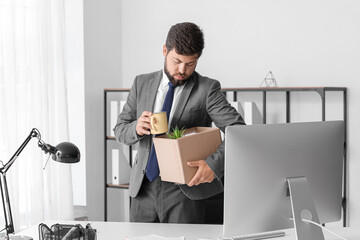 Wall Mural - Fired young man holding box with his stuff in office