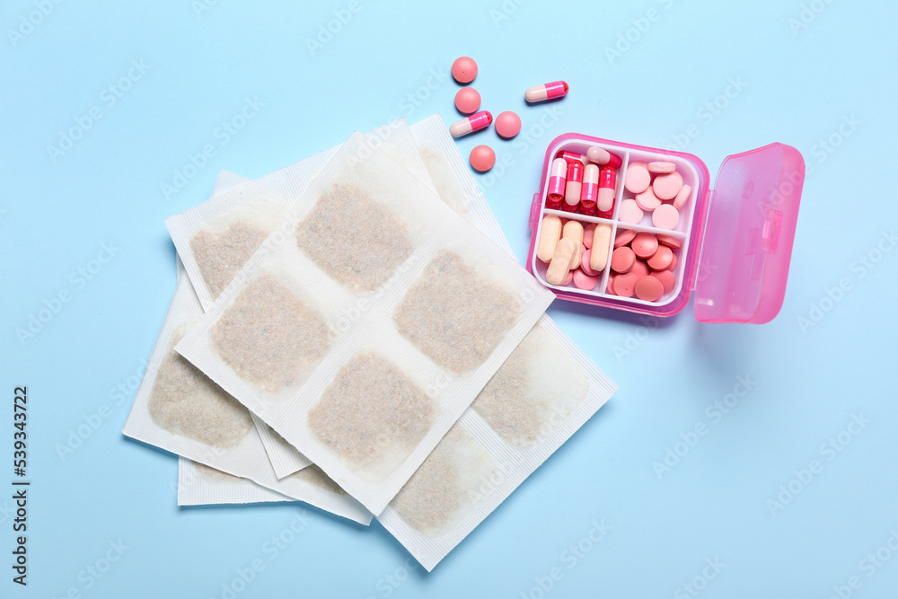 Mustard plasters and pills on blue background