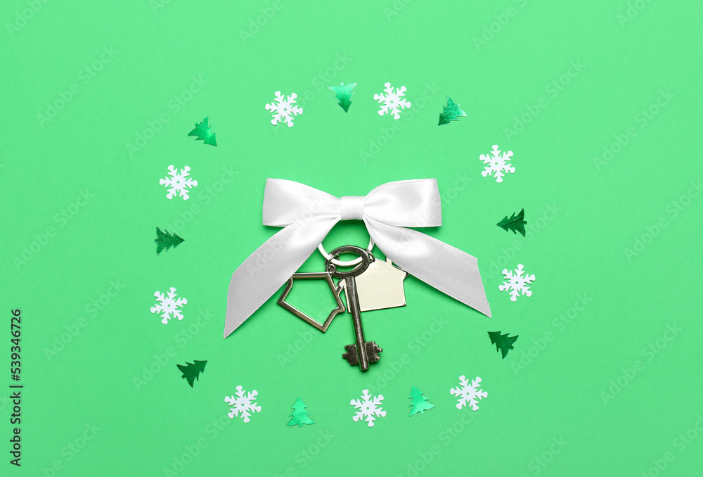 Key from new house with bow and Christmas decor on green background