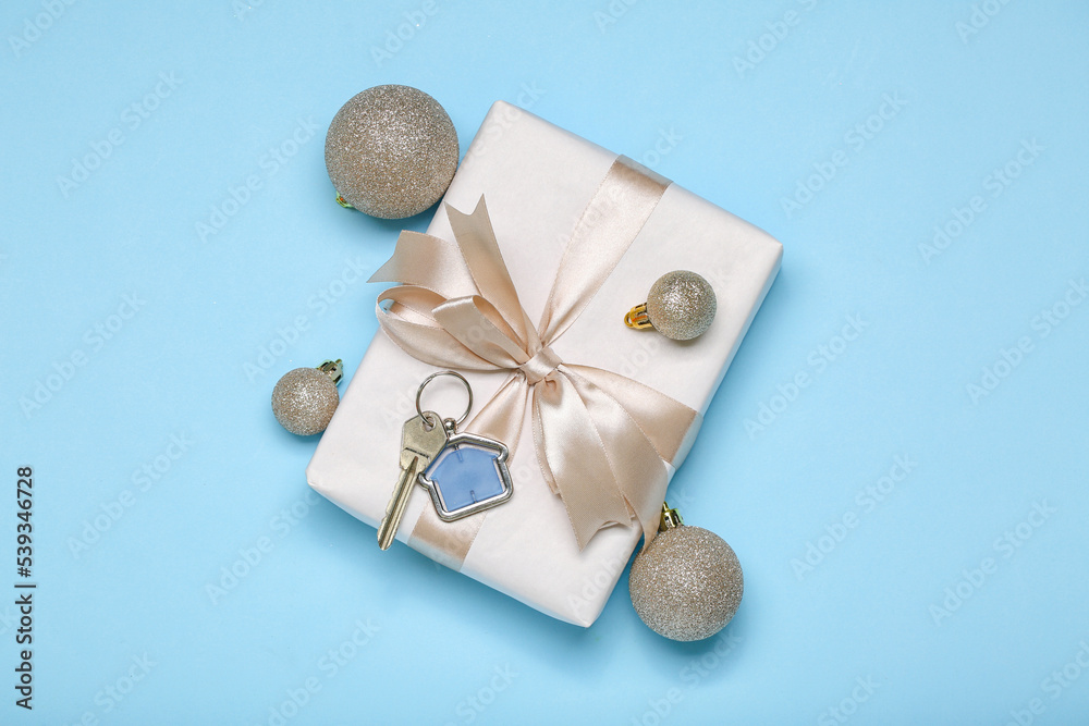 Key from new house with gift and Christmas balls on blue background