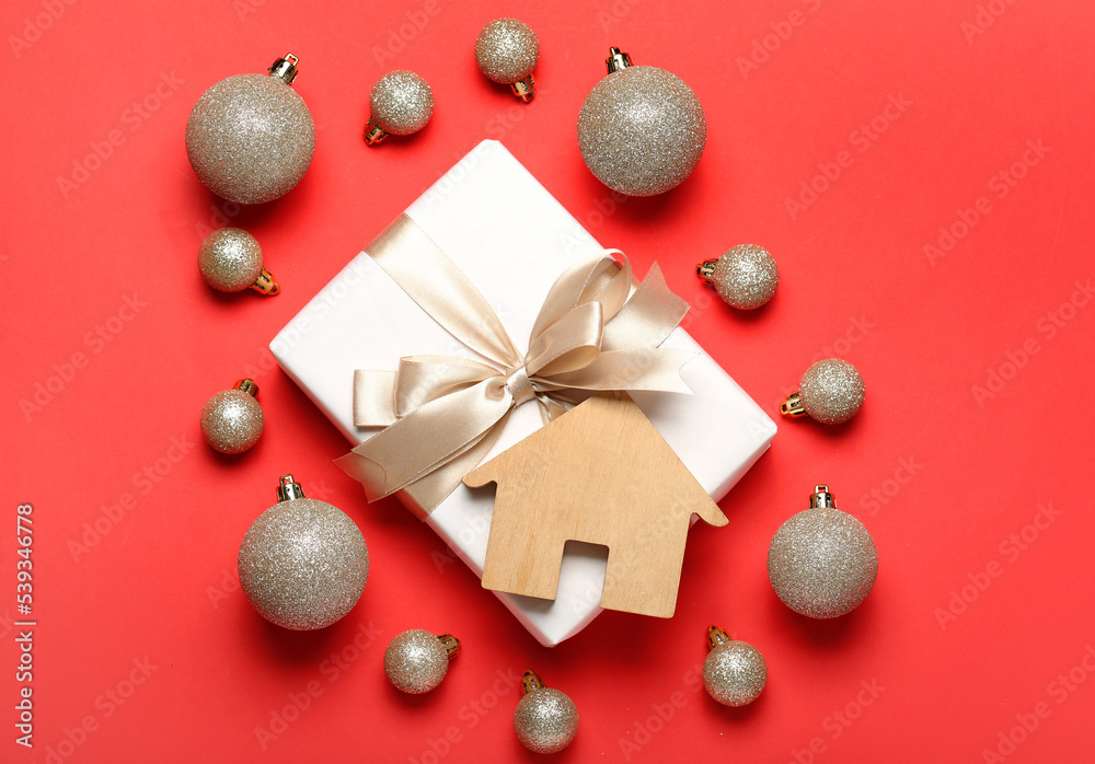 House figure with Christmas balls and gift on red background