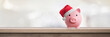 Pink piggy bank with santa claus hat on a table - saving concept for christmas