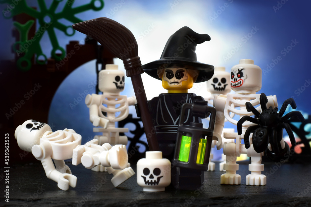 Lego minifigure scary halloween witch with skeletons and broom at dark night.  Editorial illustrative image of holiday.