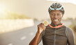 Cycling, marathon winner and gold medal by happy man holding, showing and celebrate success in road. Win, celebration and portrait of cyclist excited about fitness, health and endurance competition