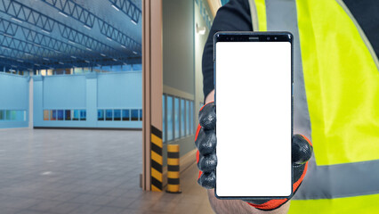 Poster - Phone is in workers hand. Smartphone with blank white screen. Phone and empty warehouses. Warehouse rental concept. Locations for rental proposals. Selective focus. Copy Space for warehouse website