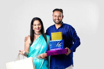 Indian Couple in Traditional clothes holding gift boxes and shopping bag on white background.