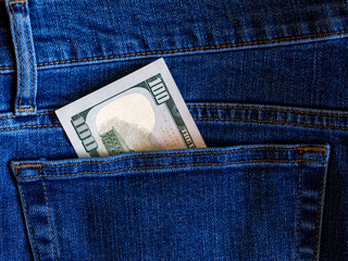 One hundred dollar banknote money in back pocket jeans pants background texture. 100 dollar bill close up Money, business, finance, saving, banking, wealth, waste concept. Exchange Rates.