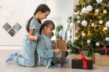 Wall Mural - two little girls with presents around the Christmas tree.