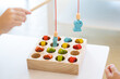 Kids are playing and finding the matched number in the wooden magnetic fishing game, using wooden fishing pole provided with magnets to attach the mouth of the fish and picking it up.