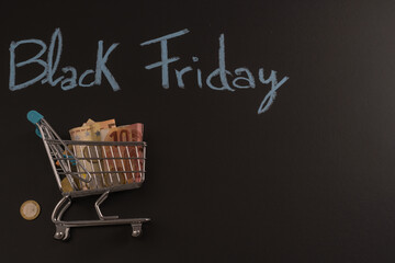 Money inside a shopping cart with Black Friday text on black background