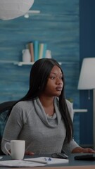 Poster - Vertical video: Afro american student sitting at desk table start typing online homework using computer browsing information on internet searching webinar courses. Black woman working remote from home
