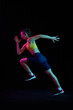 © master1305 - Dynamic portrait of young sportive woman training, running isolated on dark background in neon light. Competition, sport, fitness, speed and energy concept.