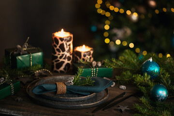 Wall Mural - Christmas table setting with empty black ceramic plate, fir tree branches and green gift boxes on dark wooden background