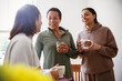 © Caia Image - Mother and young adult daughters talking and drinking at home