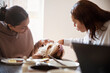 © Caia Image - Young adult sisters with dog at dining room table
