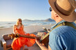 © Caia Image - Happy couple playing guitar and dancing on sunny patio with ocean view