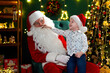 © ZaStock - Funny boy checking the red nose of Santa Claus while sitting on his lap. New Year concept