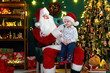 © ZaStock - Santa Clause playing with little cute boy catching his nose near Christmas tree. New Year concept