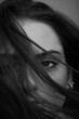 © Rytis - Close-up beautiful woman with seductive look studio portrait. Model covering part of her face with hairs by blowing wind. Mysterious and sensual look. Eye is in camera focus. Black and white image