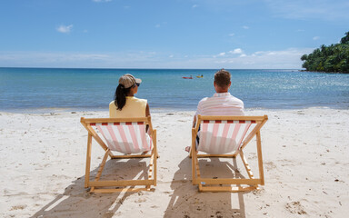 Men and women relaxing on the beach in a colorful beach chair, a Beach vacation Concept with a chair and blue sky on the tropical Island of Koh Kood Thailand. 