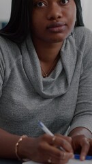 Poster - Vertical video: Portrait of student with black skin writing creative communication project for high school homework sitting at desk in living room. Teenager woman browsing graphic information on