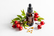 serum based on rosehip seed oil for facial skin care in a cosmetic bottle on a white background among ripe rosehip berries. moistening. nutrition.