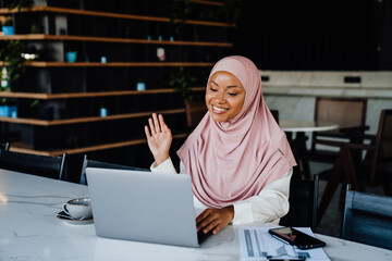 Wall Mural - Young muslim woman wearing headscarf working on laptop in office