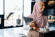 © Drobot Dean - Happy muslim businesswoman holding clipboard while working in office