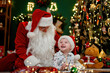 © ZaStock - Laughing boy having fun with Santa Clause lying on the floor near Christmas tree. New Year concept