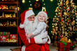 © ZaStock - Laughing little boy in Santa's hat hugging with Santa Claus near Christmas tree. New Year concept