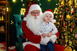 © ZaStock - Happy little boy sitting with Santa Claus near Christmas tree. New Year concept
